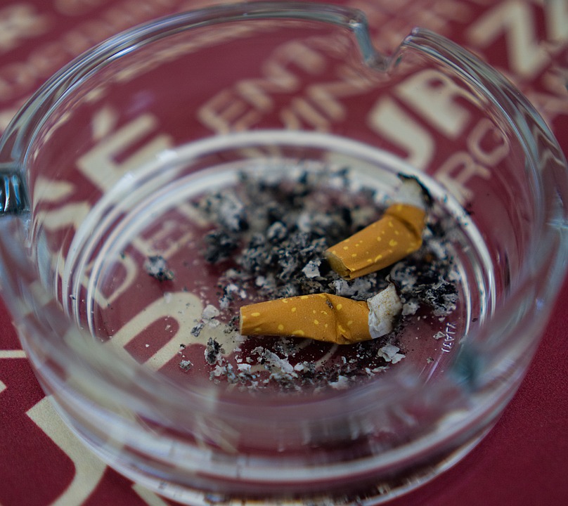 A glass ashtray filled with cigarette butts, emphasizing the importance of quitting smoking to reduce heart disease risk.