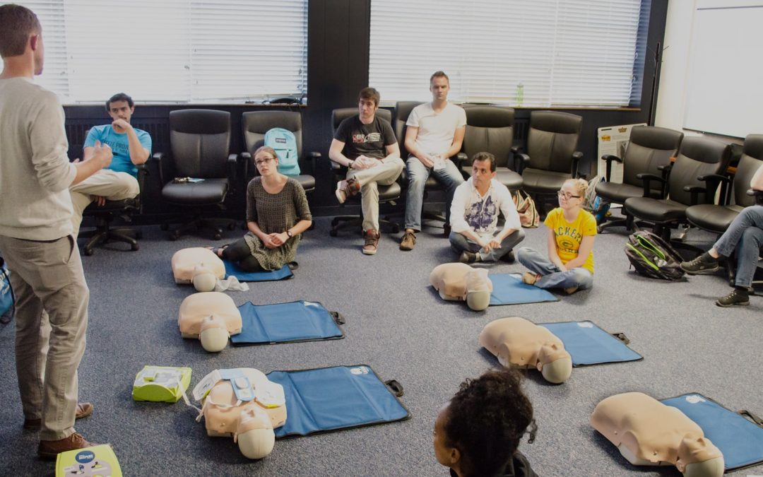 cpr and first aid instructor teaching a group of company employees at their facility.