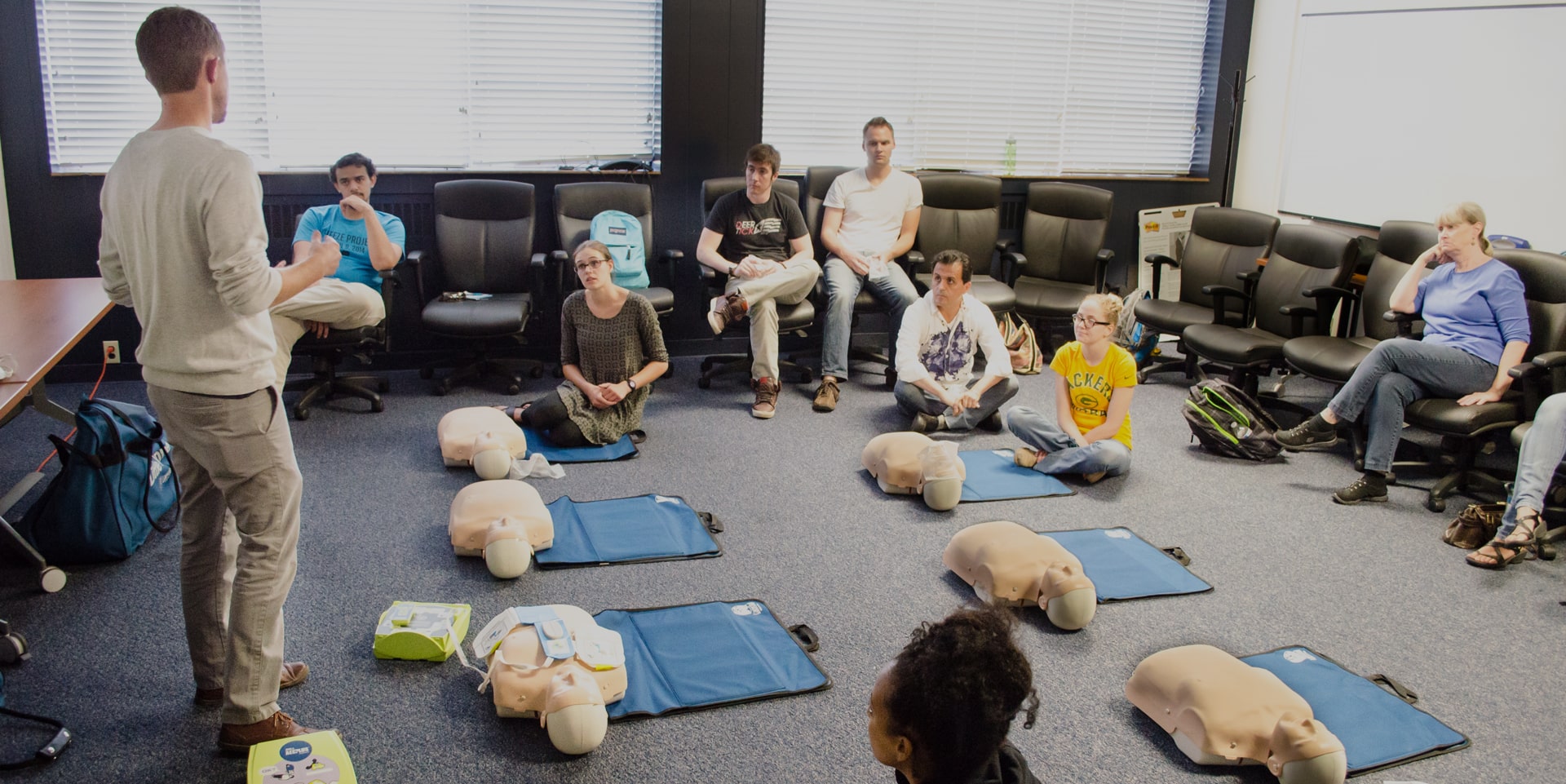 cpr and first aid instructor teaching a group of company employees at their facility.