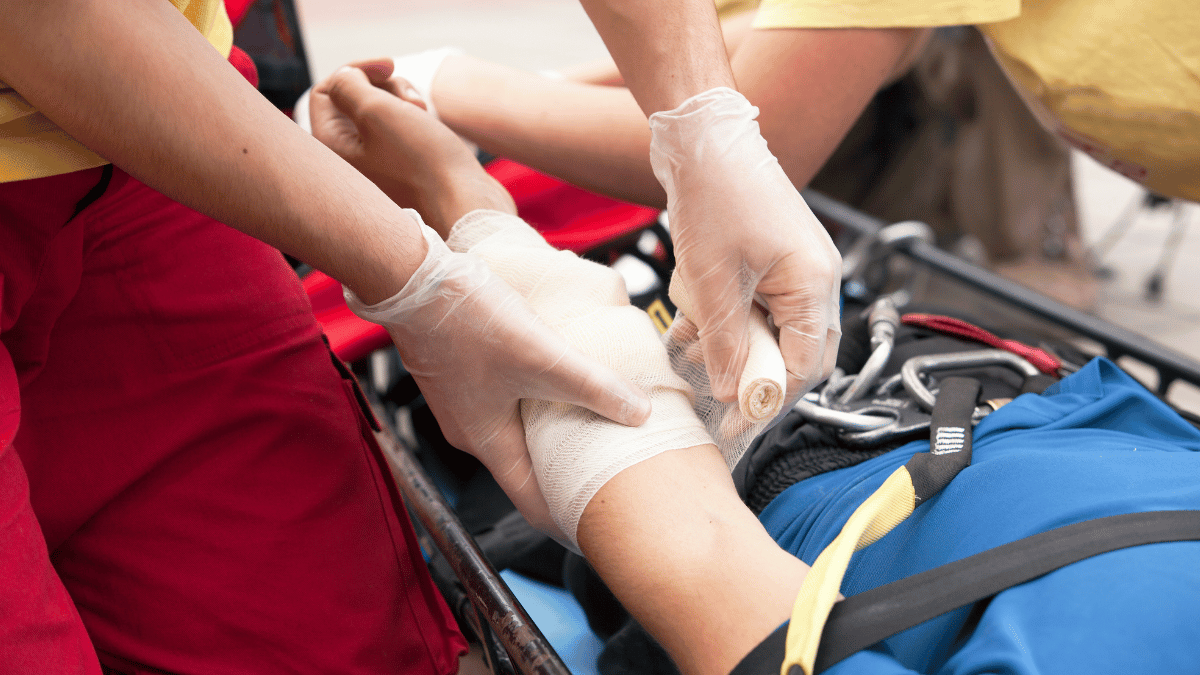 BLS-certified worker providing first aid by wrapping the arm of a patient in a rescue basket, showcasing skills learned during BLS renewal training.