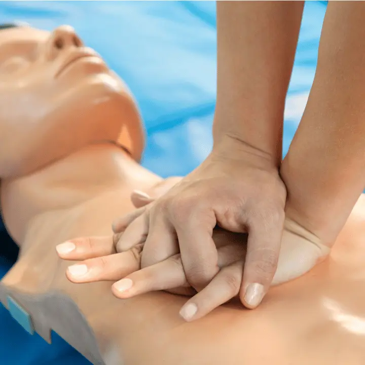Close-up of hands performing chest compressions on a CPR manikin during a first aid training class in San Diego