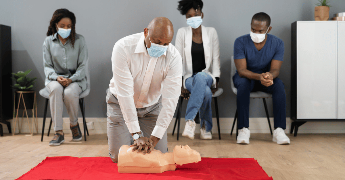 Instructor demonstrating hands-only CPR on a training mannequin while students observe during a CPR certification class in Oceanside, California.