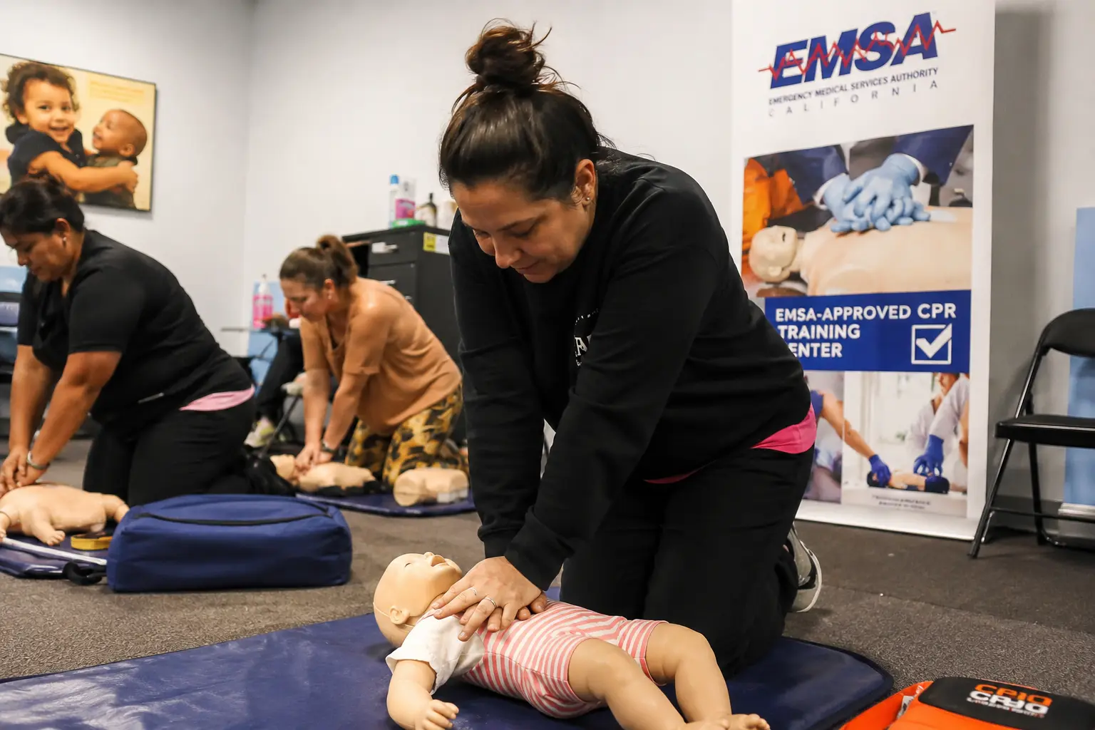 Childcare provider practicing pediatric CPR in an EMSA-approved class in San Diego